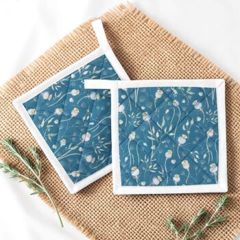 Zwei blaue Topflappen mit feinem Mohnblumen-Muster und weißer Einfassung, auf einem Jutestoff arrangiert