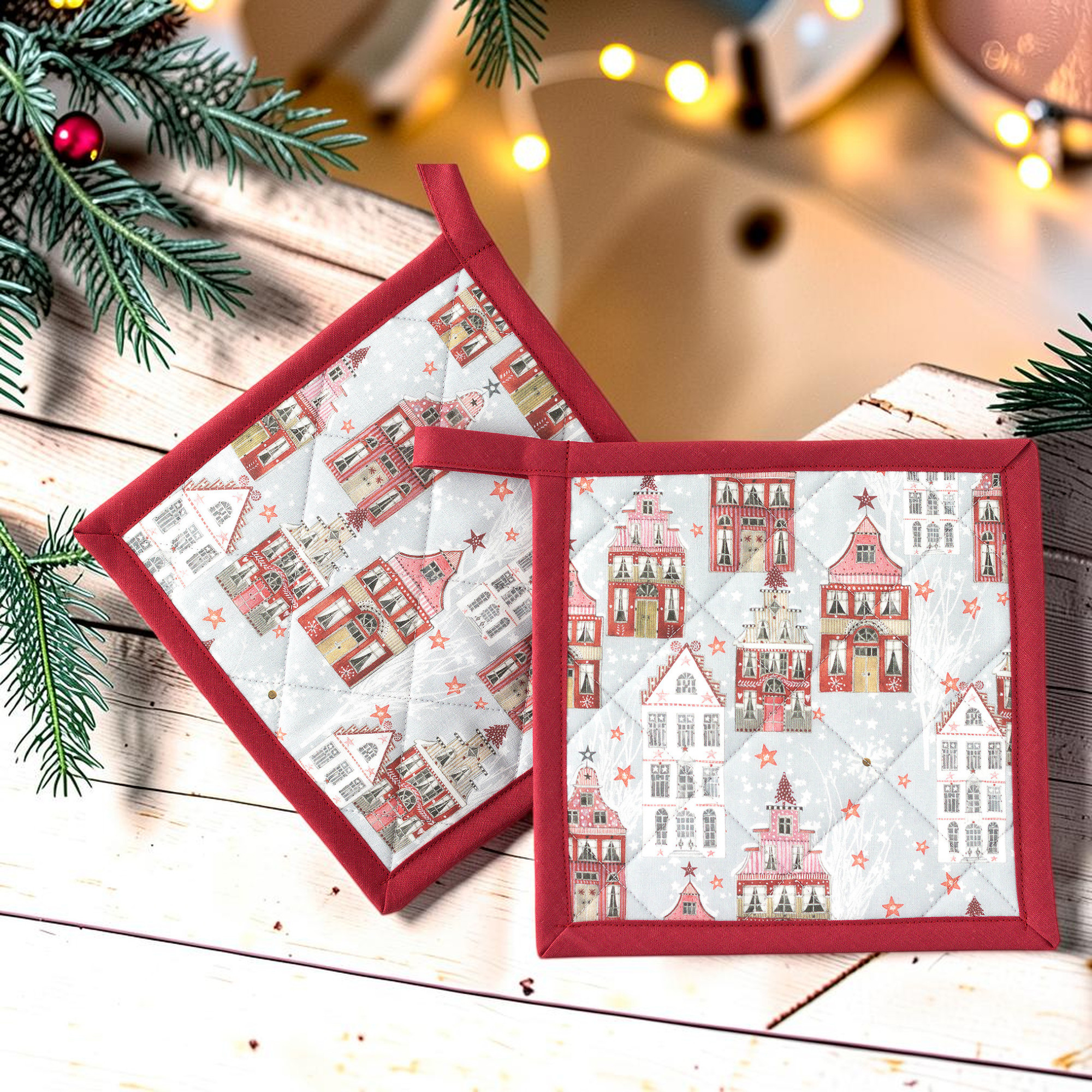Zwei Topflappen mit weihnachtlichem Häuserdorf-Motiv, rot-weiße Häuser auf hellgrauem Stoff und rote Einfassung