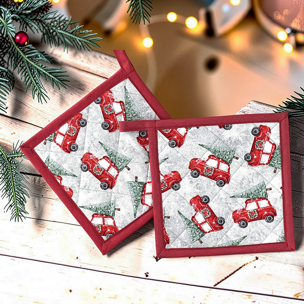 Zwei weihnachtliche Topflappen mit roten Autos und Tannenbäumen, grau-weißer Stoff mit roter Einfassung und Weihnachtsdekoration